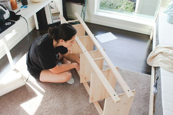 A person assembling a wooden shelf at home