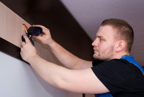 A handyman fastening a fixture to a wall with a screwdriver