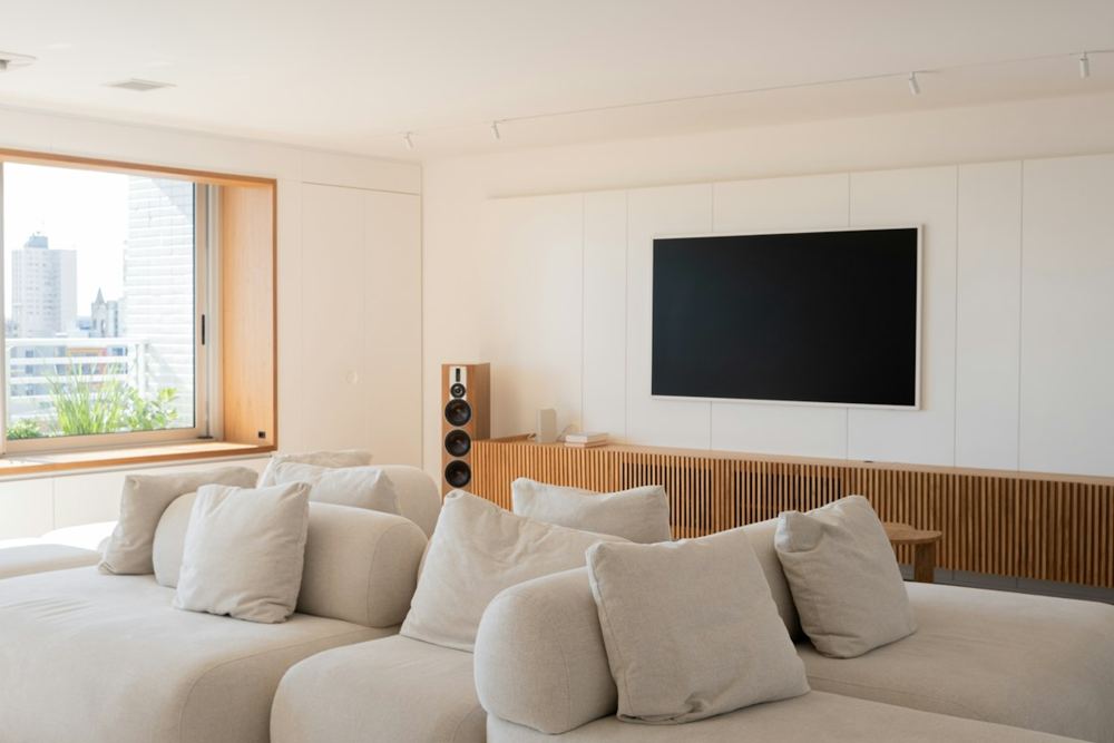A flat screen TV mounted flush on a living room wall above a low cabinet